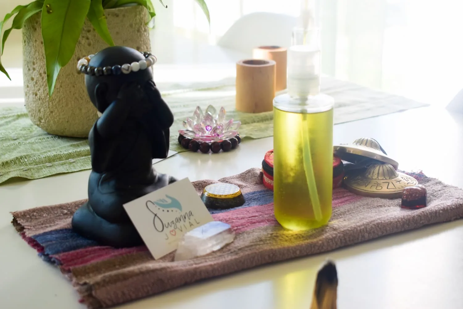 Ambiance d'un espace de soin Suzanna Jovial : huile de massage, cristaux, bougie et végétal dans une lumière douce